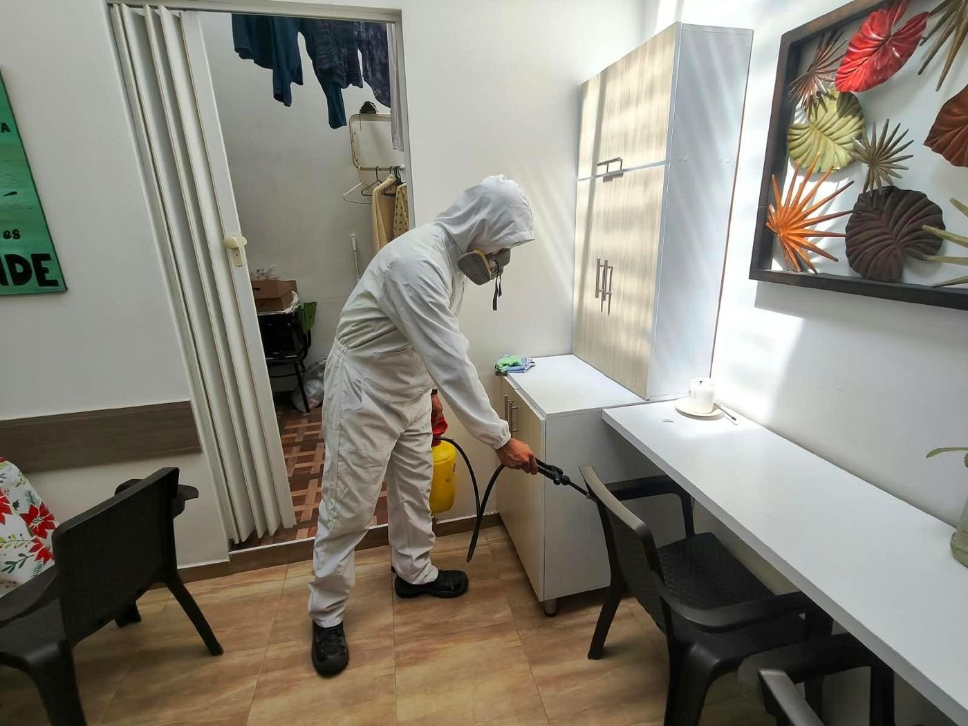 Técnico de ASIU con traje de protección fumigando un comedor